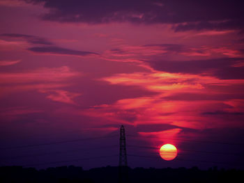 Low angle view of silhouette electricity pylon against sky during sunset
