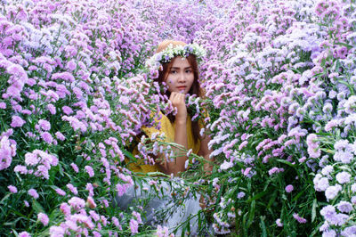 Portrait of beautiful young woman standing by flowering plants