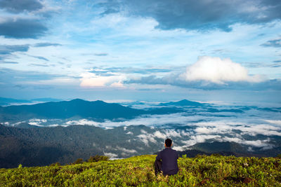 Rear view of man looking at mountains against sky