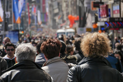 Rear view of people walking on street in city