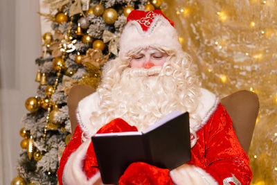 Close-up funny funky fat santa claus holding notepad, thinking about plan