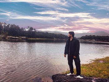 Young man looking at lake against sky