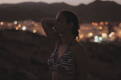 Thoughtful woman standing on field at dusk