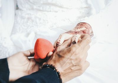 Cropped hands of bridegroom putting ring on bride during wedding ceremony