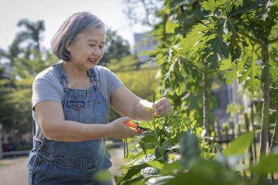 Portrait of young woman standing against plants