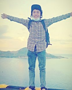 Portrait of boy standing on sea shore against sky