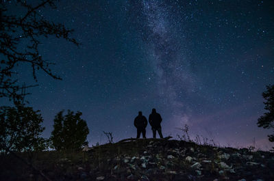 Silhouette of people standing against sky at night