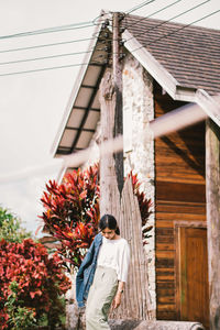 Young woman standing by house