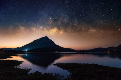 Scenic view of lake and mountains against sky at night