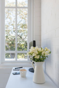 Flower vase on table by window