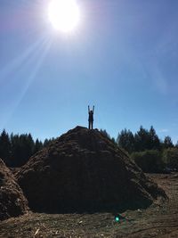 Silhouette person standing on heap against sky