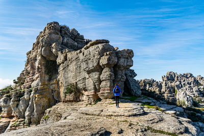 People on rock by mountain against sky