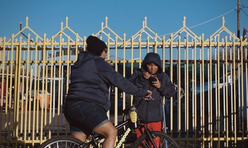 Men riding bicycle on railing against sky