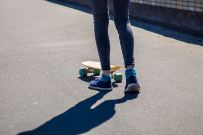 Low section of woman skateboarding on road