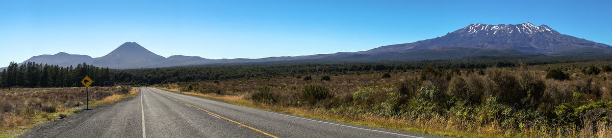 Road by mountains against clear blue sky