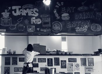 Rear view of woman standing against illuminated wall