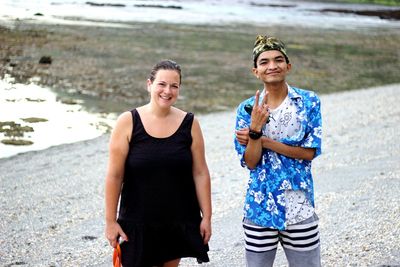 Portrait of smiling man and woman standing on beach