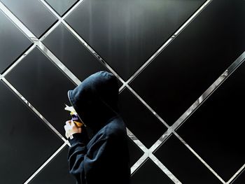 Rear view of man holding bird on window