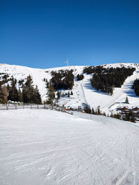 Snow covered landscape against clear blue sky