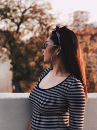 Young woman wearing sunglasses standing against tree