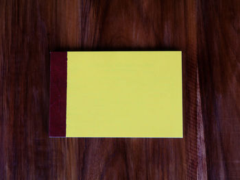 Close-up of yellow paper on wooden table