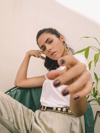 Portrait of young woman holding camera at home