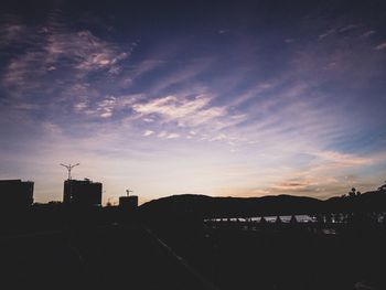 Silhouette buildings in town against sky at sunset