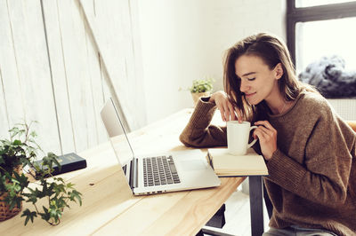 Young woman using laptop on table at home