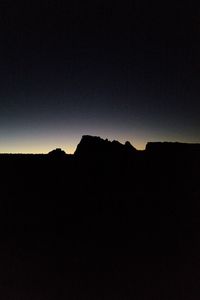 Silhouette landscape against clear sky at night