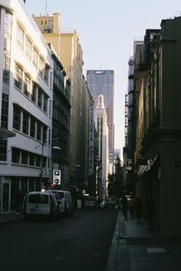 Vehicles on road amidst buildings against clear sky