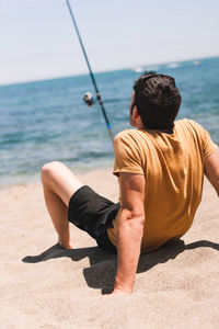 Rear view of man sitting on beach