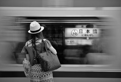 Rear view of woman standing by train moving at subway station