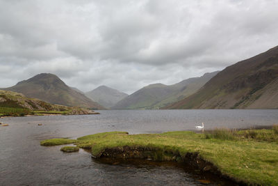 Scenic view of lake and mountains against cloudy sky