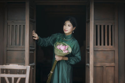 Full length of a smiling young woman holding door