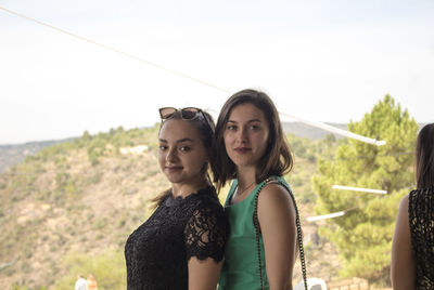 Portrait of smiling young woman standing against sky