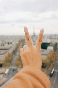 Close-up of human hand against sky