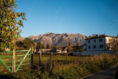 Houses by mountains against clear blue sky