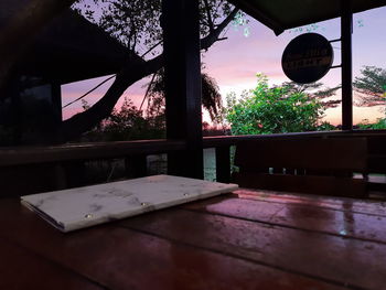 Table by trees against sky seen through window