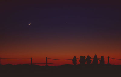 Silhouette people on mountain against sky at night