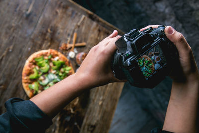 Cropped hands photographing pizza using camera