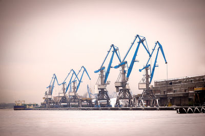 Port cranes on dock against clear sky