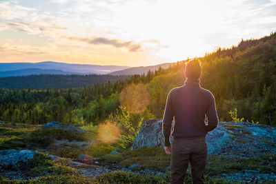 Rear view of man looking at mountain during sunset