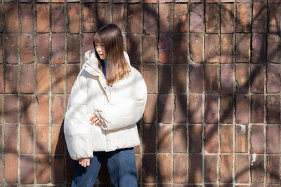 Young woman standing against wall