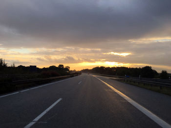 Empty road along countryside landscape at sunset