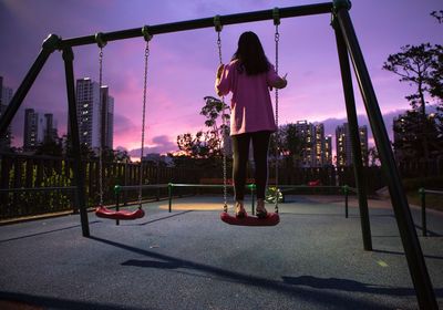 Rear view of boy playing on playground against sky