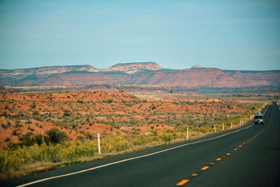 Scenic view of road by mountain against clear sky