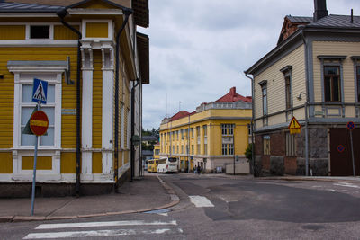 Road by buildings in city against sky