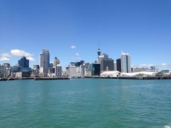 Sea by buildings against clear blue sky