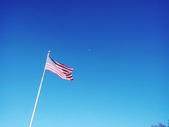 Low angle view of american flag against clear blue sky