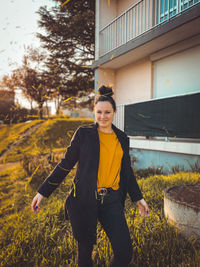 Portrait of smiling young woman standing against building